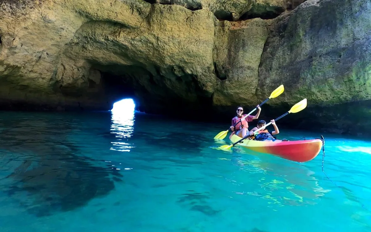 A kayak on clear water below the golden cliffs of the Algarve
