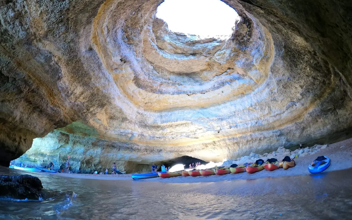 Kayakers paddling in a line below the golden cliffs of the Algarve