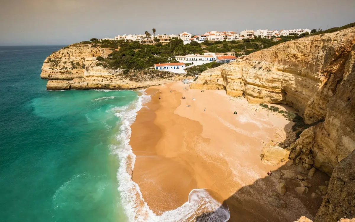 An aerial view of a sandy Algarve beach below limestone cliffs