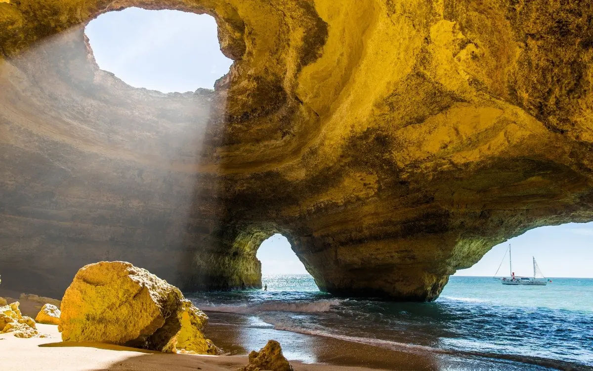 A private boat beside a sea arch on the Algarve coast