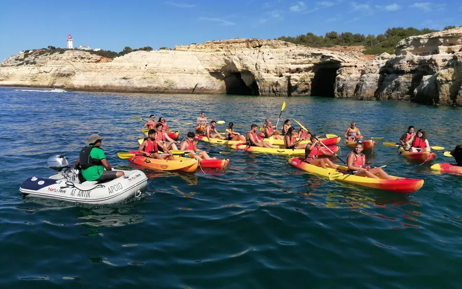 Kayakers paddling in a line below the golden Algarve cliffs