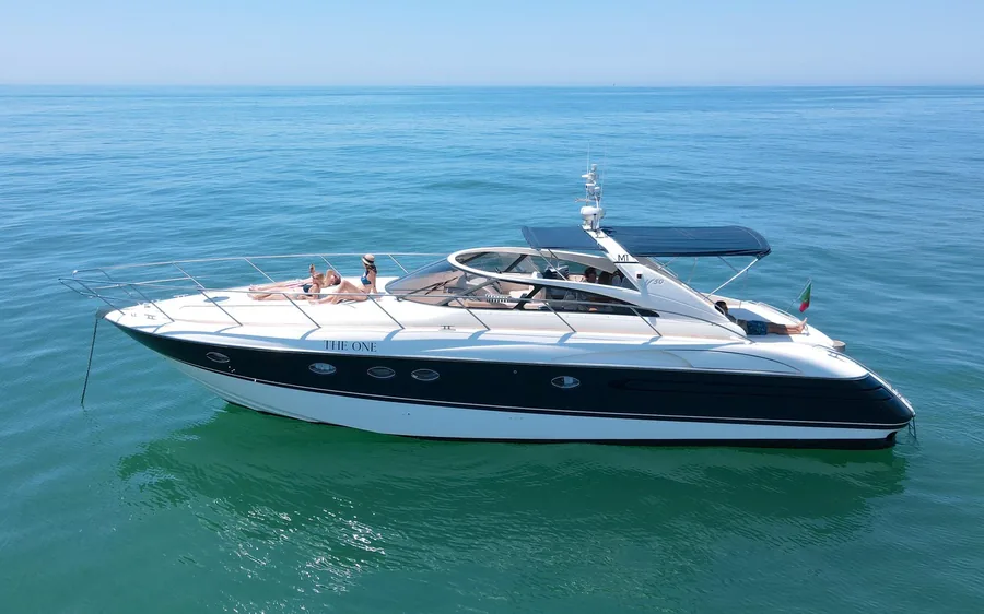 A white motor yacht at anchor on flat water off the Algarve coast