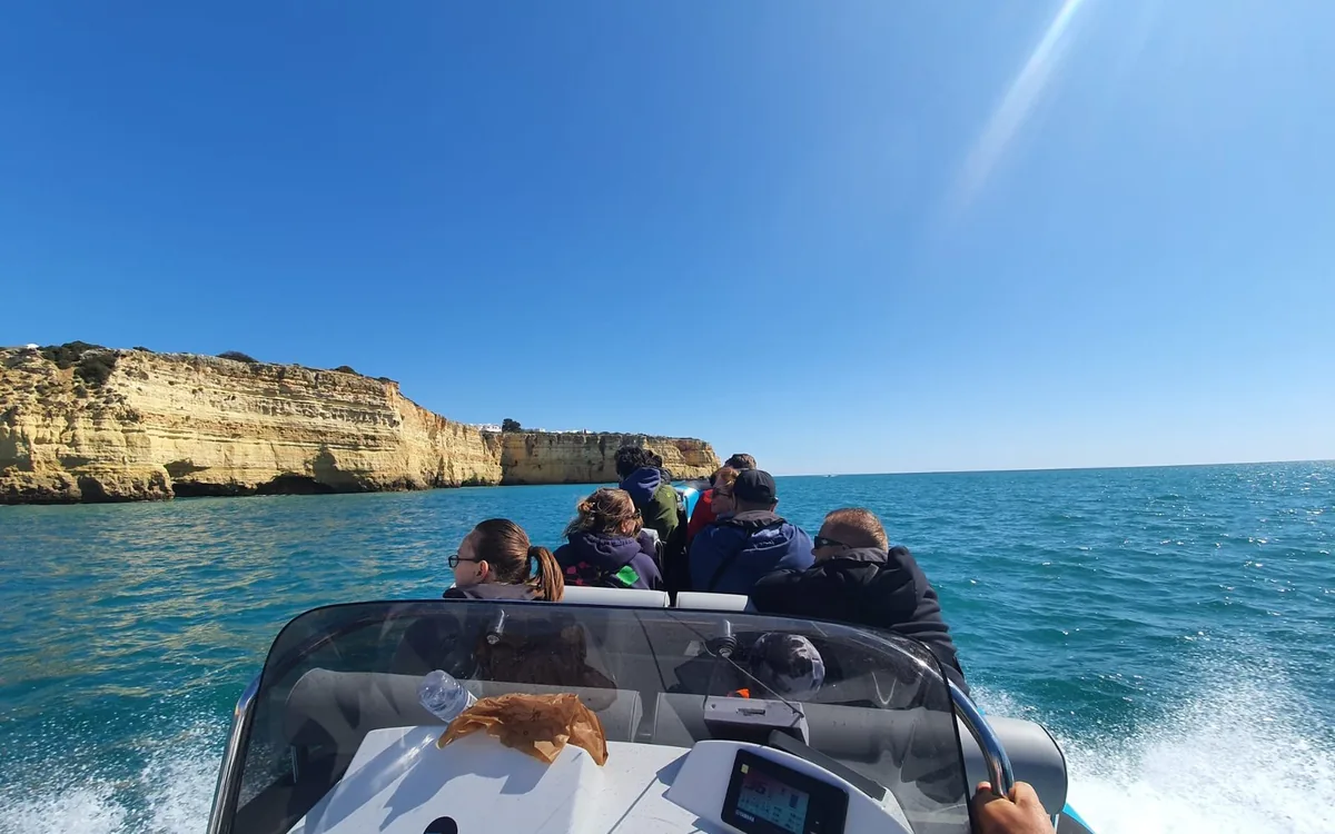 A speedboat running along the golden cliffs of the Algarve coast